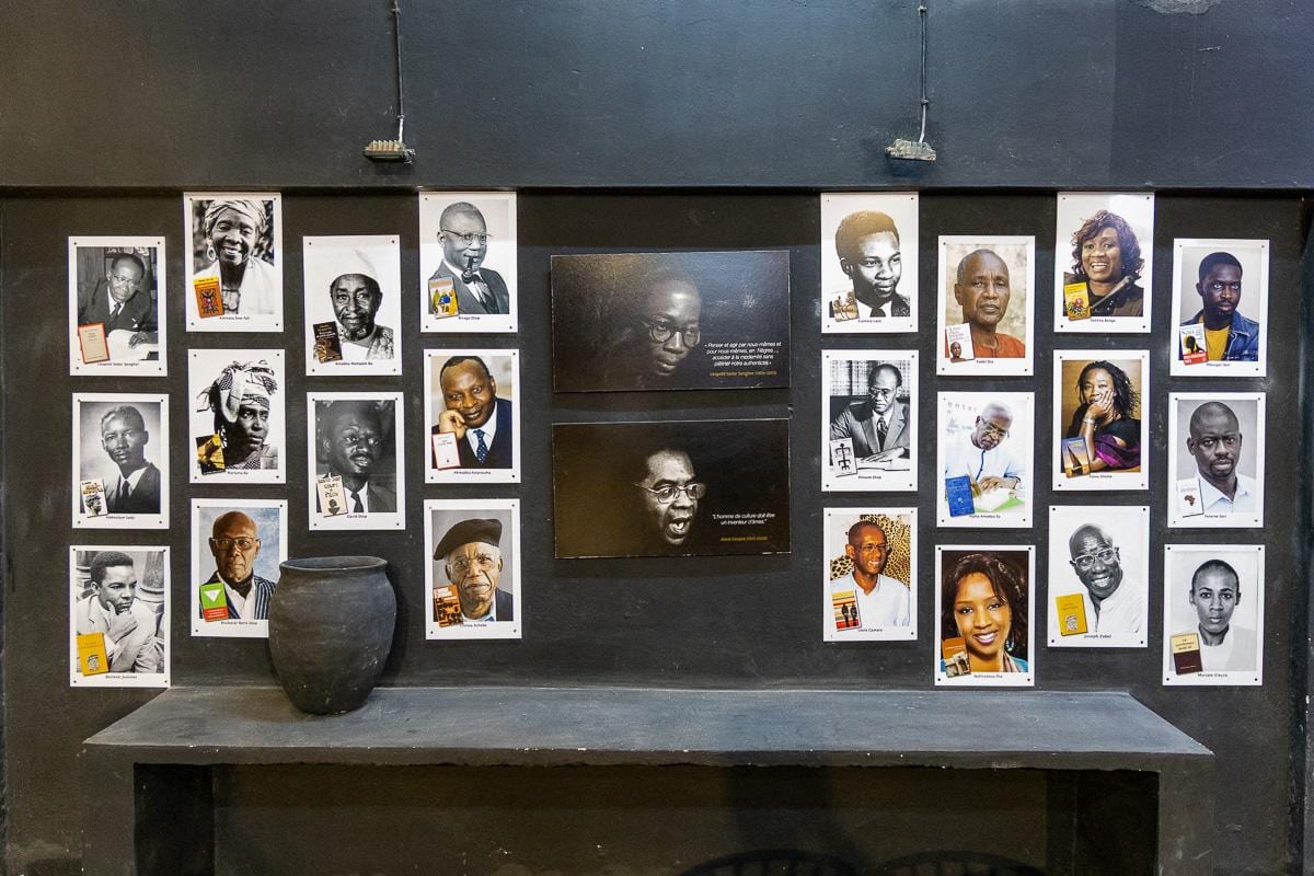 Mural de retratos impresos junto a una tinaja de barro en una sala del MuPho